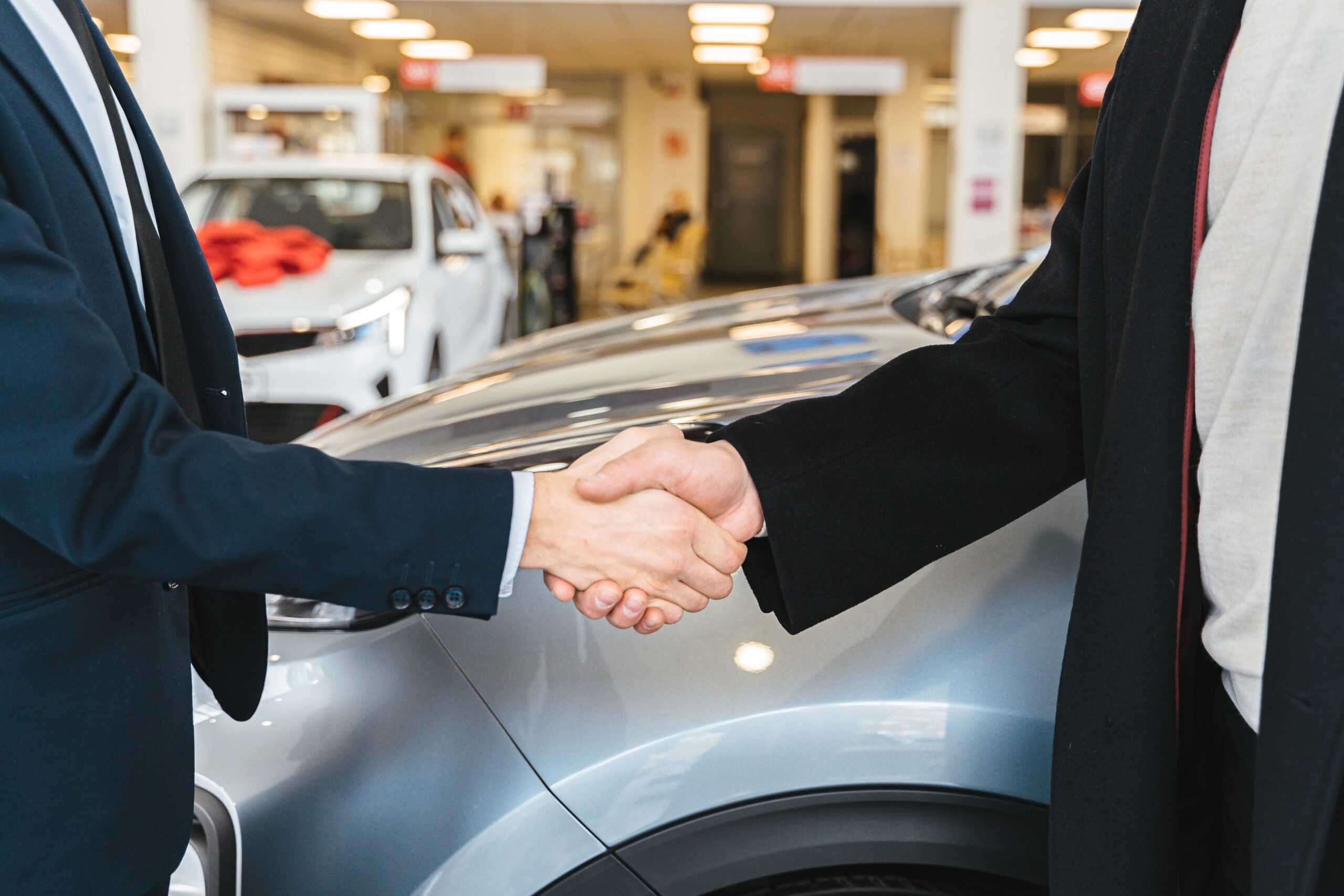 Two men shaking hands near a car, showing a positive interaction or agreement between them.